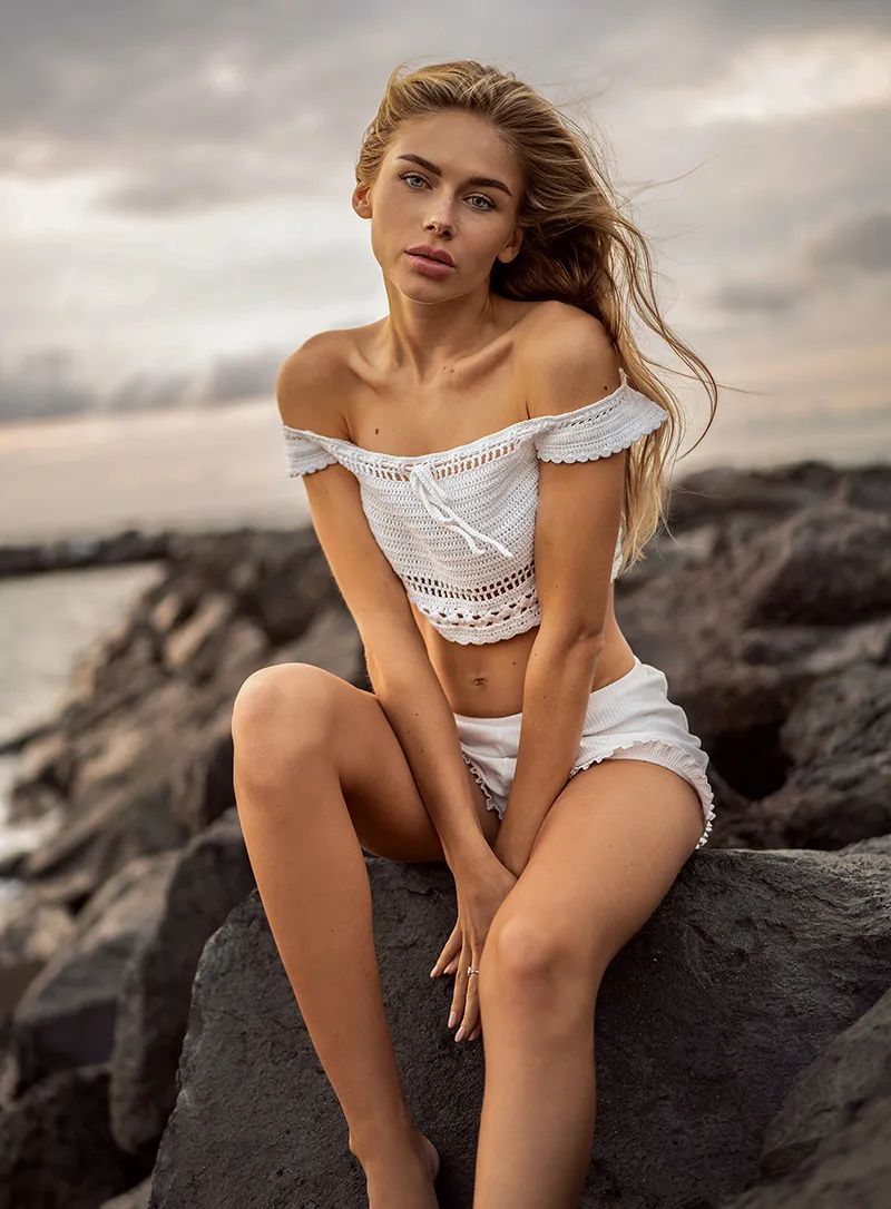 Blonde in white outfit sitting on rocks - Female
