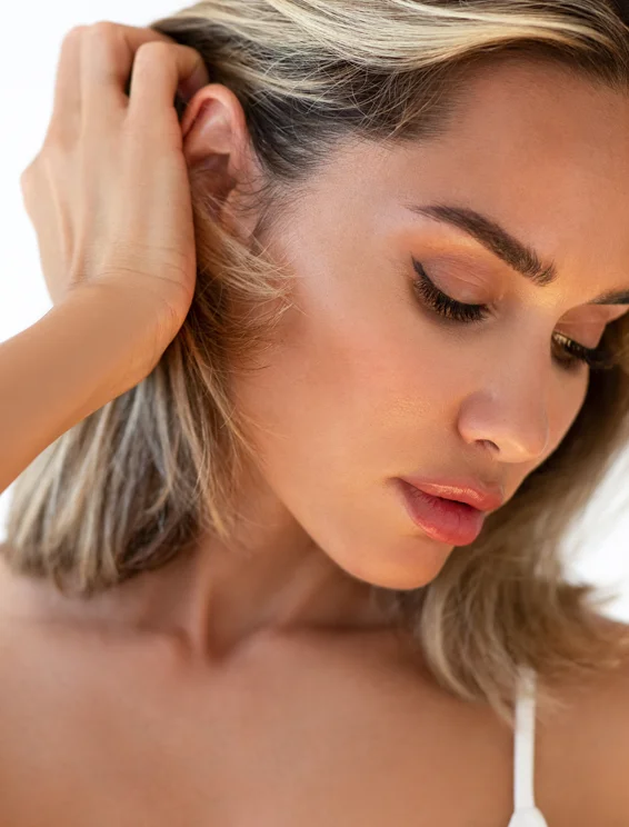 Benefits of earlobe repair in Tampa - woman pulling hair back exposing ear